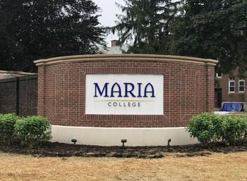 College sign in brick wall at entrance opened in 2020, adjacent to Marian Hall
