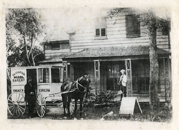 black and white image of a horse and carriage outside of bakery
